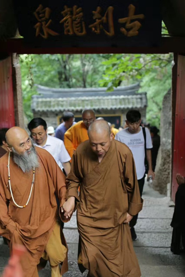 延参法师与龙泉寺的方丈主持携手游览寺院美景,走在禅林的石路上,同参