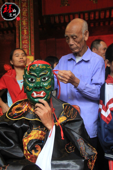 (村里的老人给"判官"带面具中,专注且严肃,也是代表对神的尊敬.